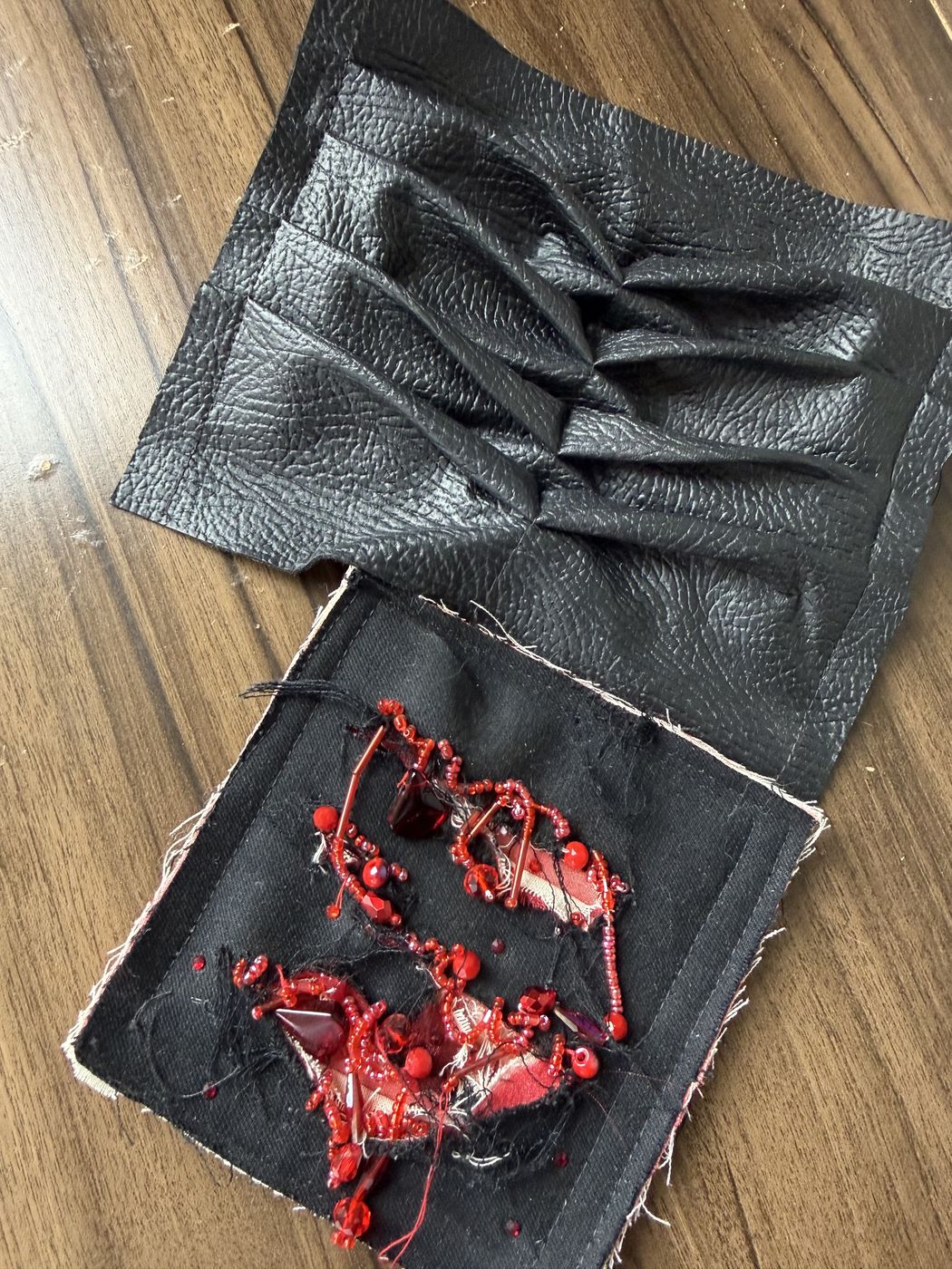 Pruebas en cuero negro: pliegues y bordado rojo