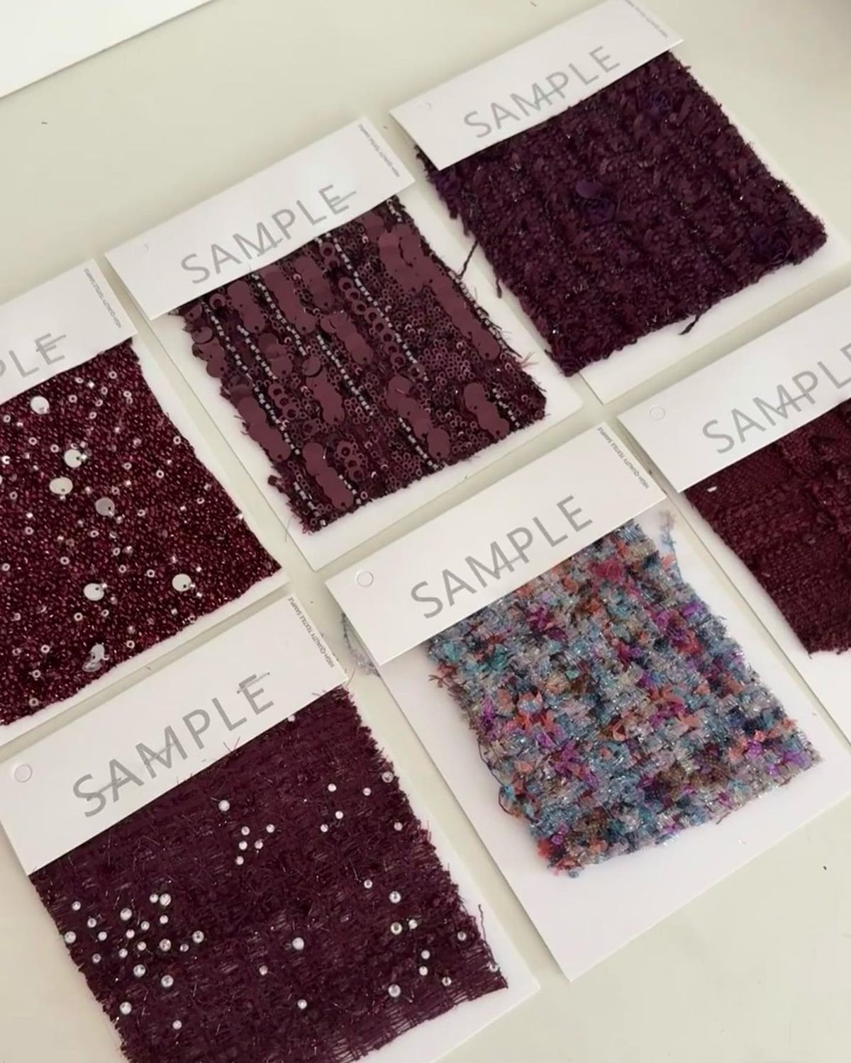 Muestras textiles en tonos burdeos con pedrería y tweed